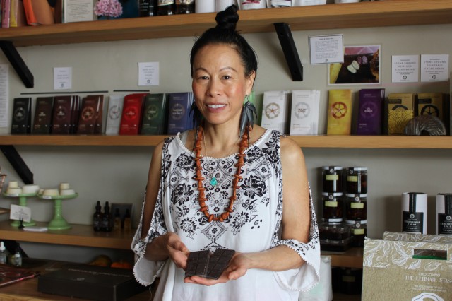Patricia Tsai holding a bowl and standing in front of shelves of chocolate bars