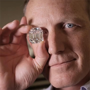 Aaron Celestian holding a rectangular shaped diamond over his eye